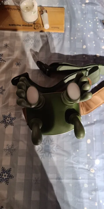 Le châle de massage Nuquea vu de dessus sur un couvre-lit à flocons, ses deux têtes et sa sangle